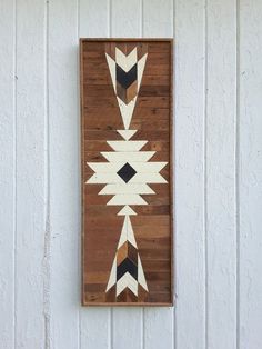 a wall hanging made out of wood and painted with black and white geometric designs on it