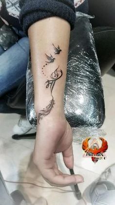 a woman's hand with a tattoo on it that has a bird flying above her head