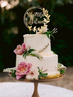 a wedding cake with pink flowers and greenery on top