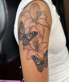 a woman's arm with flowers and butterflies tattoo on her arm, which is black and white