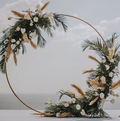 a wedding arch with flowers and greenery on the beach in front of the ocean