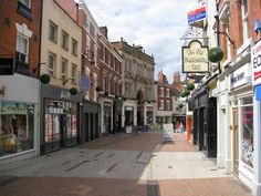 an empty city street with shops and stores on both sides, surrounded by brick buildings