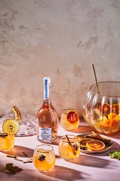 a table topped with wine glasses filled with liquid and orange slices next to each other