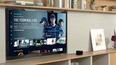 a flat screen tv sitting on top of a wooden shelf next to a bookcase