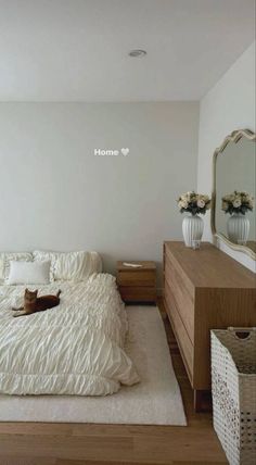 a cat is laying on the bed in a bedroom with white walls and wood flooring