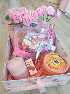 a pink gift box filled with lots of beauty and personal care products on top of a wooden floor