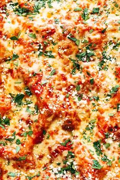 a pizza with cheese, sauce and herbs is shown in close up view from above