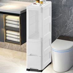 a white toilet sitting next to a tall cabinet in a bathroom with marble walls and flooring