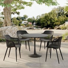 an outdoor table with four chairs and a tree in the backgrounge area