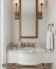 a bathroom with a sink, mirror and gold faucet