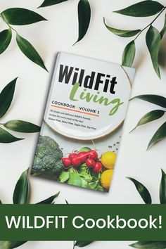 the book wildfit living cookbook is surrounded by green leaves and vegetables on a white background