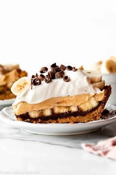 a piece of banana cream pie on a white plate with chocolate chips and whipped cream