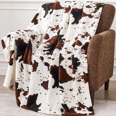 a brown and white cow print blanket sitting on top of a couch next to a chair