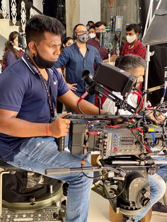 a man sitting in front of a camera on top of a tripod next to other people