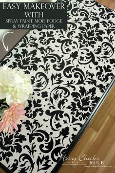 a flower is sitting on top of a table with a black and white damask pattern