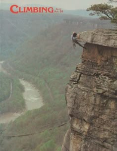 a man is climbing up the side of a cliff with a river in the background