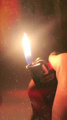 a person holding a lighter in their hand with the light on it's side