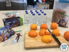 some oranges are sitting on a cutting board next to water bottles and other items