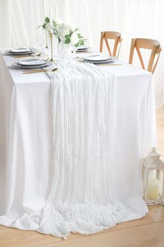 the table is set with white linens and place settings for two people to sit at