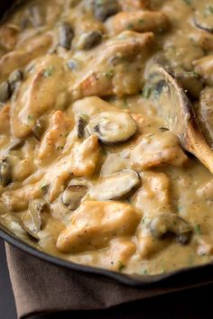 a skillet filled with chicken and mushrooms covered in gravy on top of a table