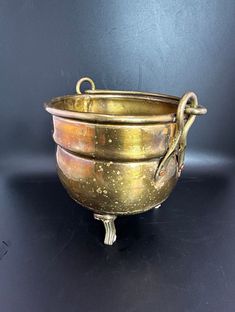 an antique brass bowl with handles on a black table