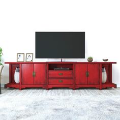 a red entertainment center with two vases and a television on it's stand