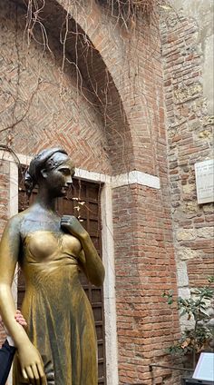 a statue of a woman in front of a brick building with vines growing over it