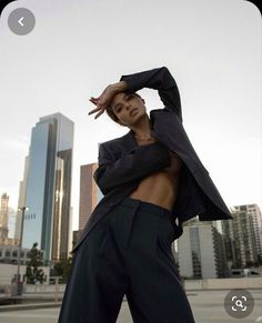 a woman is posing in front of some tall buildings