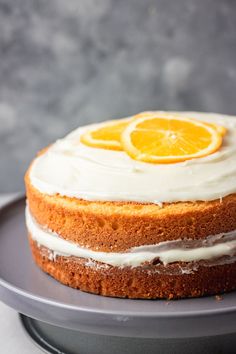 there is a cake with icing and orange slices on the top, sitting on a plate