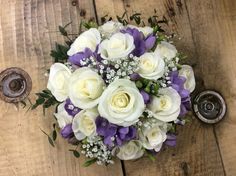 a bouquet of white and purple flowers sitting on top of a wooden table