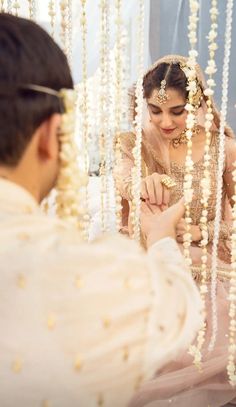 a man and woman sitting next to each other in front of a mirror with beads hanging from the ceiling