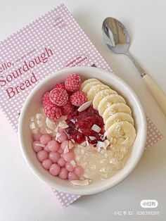 a bowl of cereal with raspberries, bananas and other toppings next to a spoon