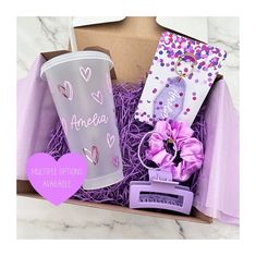 an open box containing a cup, pink hair bow and purple ribbon with the words ameria written on it