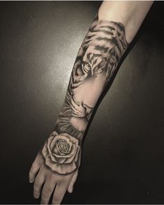 a hand with a tiger and rose tattoo on the left arm, it is black and white