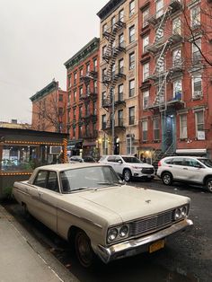 an old car is parked on the side of the road in front of some buildings