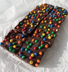 a piece of chocolate with m & m candies on it sitting on wax paper