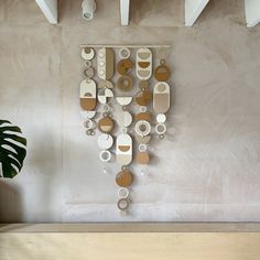 a wall hanging made out of plates and cups on a wooden shelf next to a potted plant