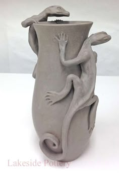 a gray vase with a lizard on it's side and another creature in the middle