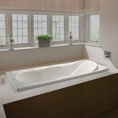 a large white bath tub sitting next to a window