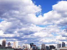 a city skyline is shown with clouds in the sky and buildings on the other side