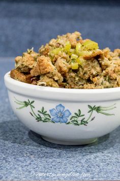 a white bowl filled with food sitting on top of a blue tablecloth covered floor