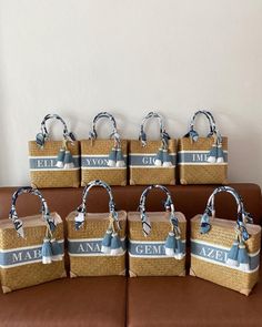 six woven bags are sitting on a brown couch with blue ribbon around the handles and sides