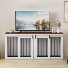 a flat screen tv sitting on top of a white cabinet next to a wooden floor