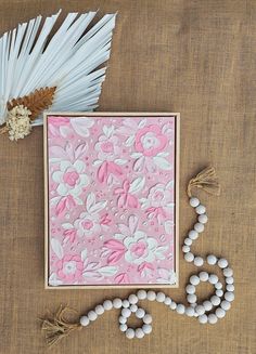 a pink and white greeting card with tassels next to it on a table