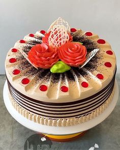 a cake decorated with red roses and chocolate sprinkles on top of a table