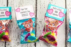 three bags of candy sitting on top of a wooden table