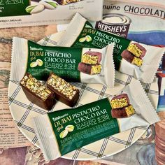 four pieces of chocolate sitting on top of a plate next to some candy bar wrappers