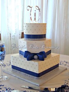 a three tiered wedding cake with blue ribbon and diamond decorations on the top layer