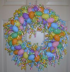 a wreath with balloons and streamers hanging from the front door