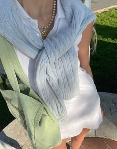 a woman sitting on a bench wearing a white shirt and green scarf over her shoulders